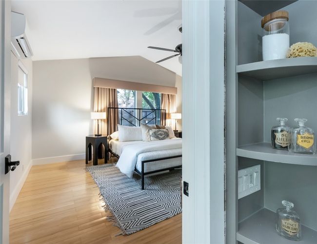 Bedroom featuring vaulted ceiling, baseboards, a ceiling fan, wood finished floors, and a wall mounted AC | Image 16