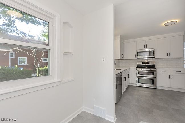 Kitchen with a wealth of natural light, backsplash, light tile patterned floors, and stainless steel appliances | Image 20