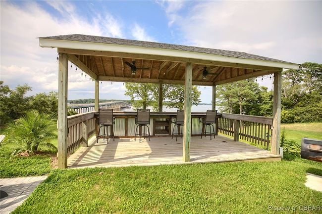 Deck featuring exterior bar, a gazebo, ceiling fan, and a lawn | Image 20