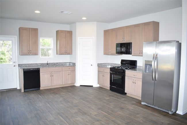 Kitchen featuring black appliances, dark wood-type flooring, recessed lighting, and light stone counters | Image 10