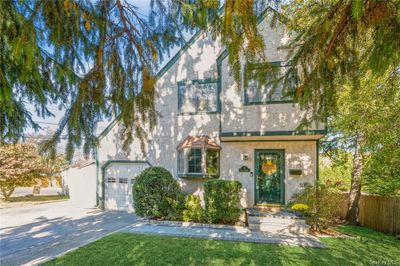 Tudor-style house featuring a front lawn and a garage | Image 1