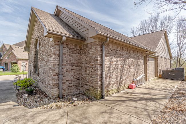 view of home's exterior with a Golf Cart Bay, a shingled roof, brick siding, and a Golf Cart Path | Image 47