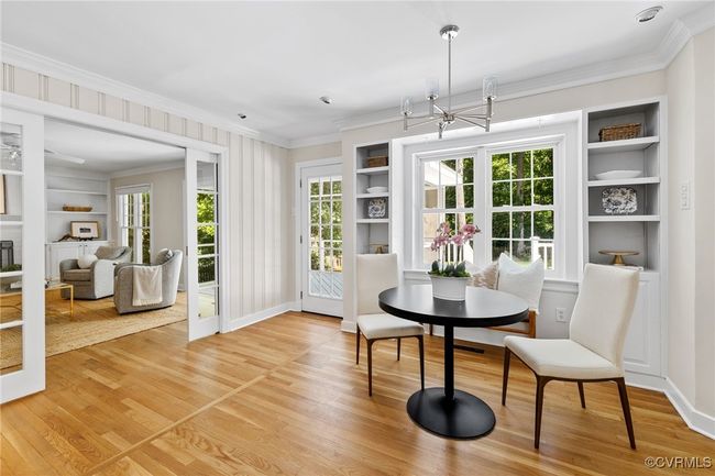 View of eat-in area offering lots of space for a table, large window, a chandelier, built-in cabinetry and shelving, hardwood flooring, crown molding, and recessed lights. There is also a door to the deck and a view of the family room which offers pocket French doors! | Image 17