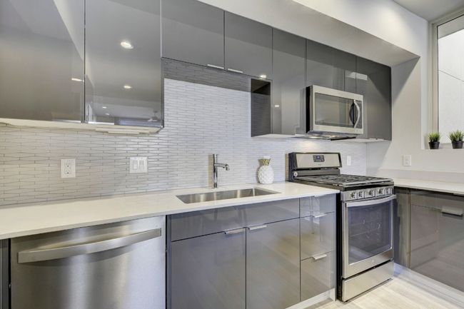 Kitchen featuring stainless steel appliances, gray cabinetry, decorative backsplash, modern cabinets, and recessed lighting | Image 12
