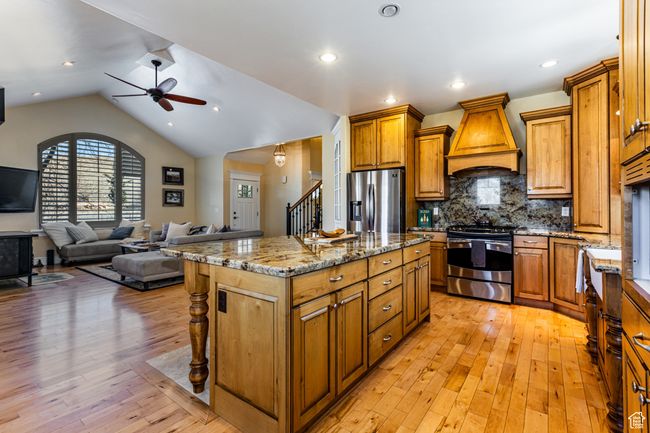 Kitchen with a kitchen island, ceiling fan, appliances with stainless steel finishes, custom exhaust hood, and brown cabinets | Image 5