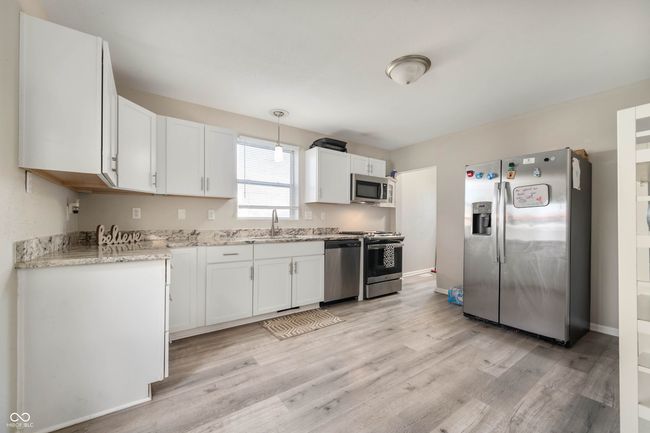 kitchen featuring a sink, light wood-style floors, white cabinetry, stainless steel appliances, and light stone counters | Image 10