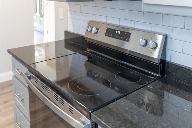 Kitchen featuring decorative backsplash, wood-style flooring, and stainless steel electric range | Image 52