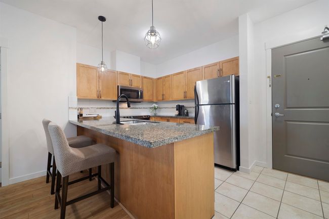 Kitchen with a peninsula, appliances with stainless steel finishes, a sink, and baseboards | Image 6