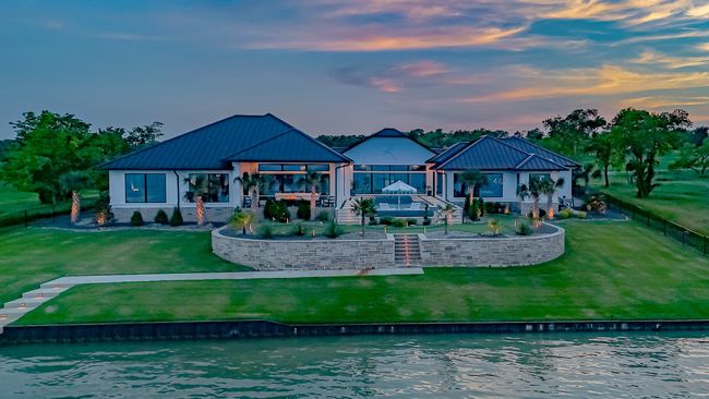 Back of property with metal roof, a lawn, a patio area, a fenced backyard, and a water view | Image 38