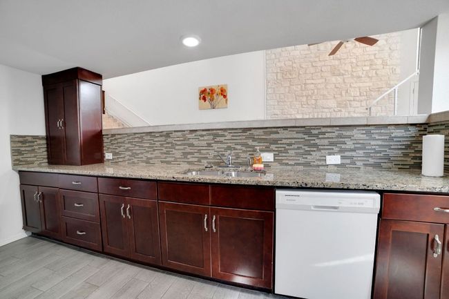 Kitchen with an abundance of counter and cabinet space, stainless steel appliances, granite countertops, laundry room and recessed lighting | Image 11