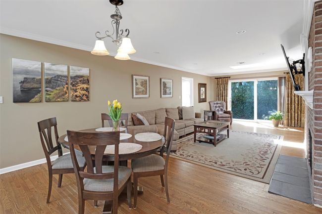Dining space featuring crown molding, an inviting chandelier, baseboards, a fireplace, and wood finished floors | Image 13