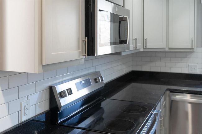 Kitchen featuring decorative backsplash, gray cabinets, and appliances with stainless steel finishes | Image 49