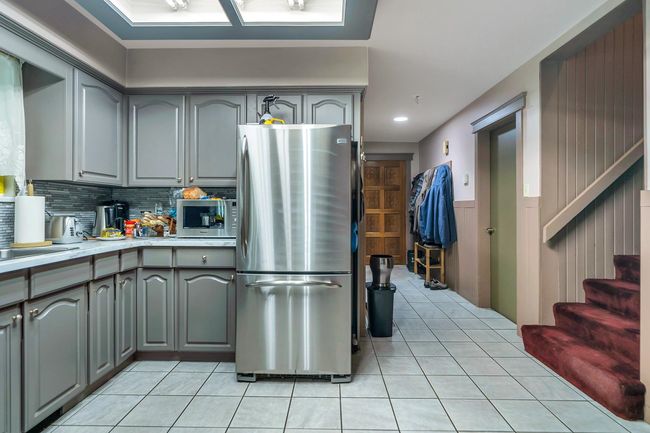 Kitchen with stainless steel appliances, light tile patterned flooring, and gray cabinets | Image 8