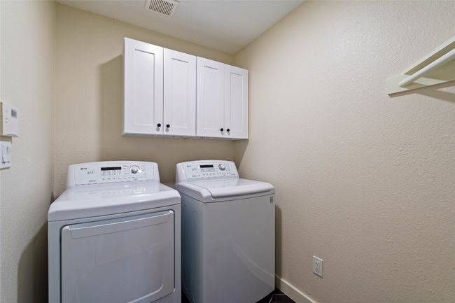 Washroom featuring visible vents, cabinet space, and washer and clothes dryer | Image 26