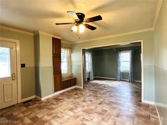 Foyer featuring plenty of natural light, ceiling fan, baseboards, light stone finish floors, and ornamental molding | Image 5