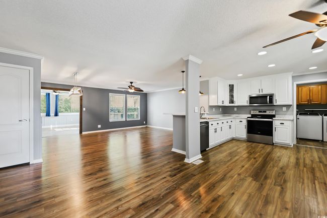 Kitchen with appliances with stainless steel finishes, a ceiling fan, washing machine and clothes dryer, ornamental molding, and light countertops | Image 8