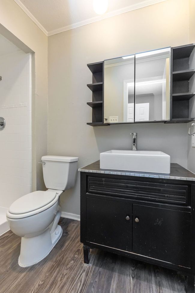 Bathroom featuring a tile shower, crown molding, toilet, vanity, and wood finished floors | Image 27