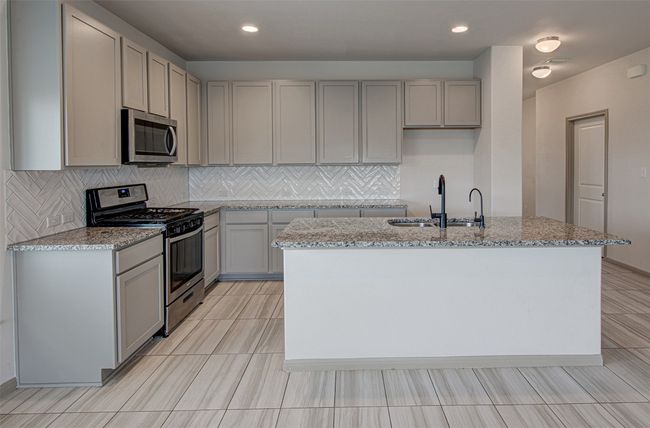 Kitchen with stainless steel appliances, a sink, gray cabinets, light stone countertops, and recessed lighting | Image 12