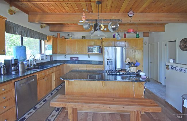Kitchen featuring appliances with stainless steel finishes, a kitchen island, dark wood-type flooring, a wooden ceiling with exposed beams, and dark stone countertops | Image 47