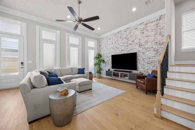 Living area featuring ornamental molding, ceiling fan, light wood finished floors, stairs, and recessed lighting | Image 4
