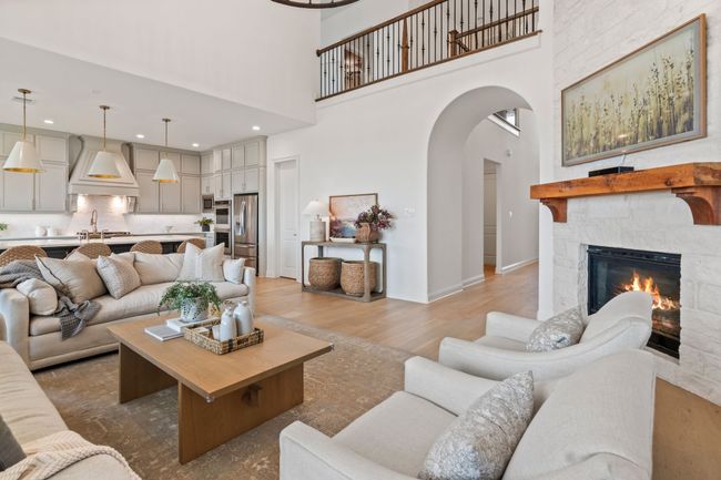 Living room featuring arched walkways, wood finished floors, a towering ceiling, a fireplace, and recessed lighting | Image 9