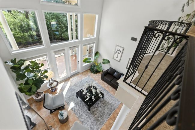 Living area with a towering ceiling, stairway, and tile patterned floors | Image 36