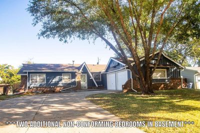 View of front of property featuring a front yard and a garage | Image 1