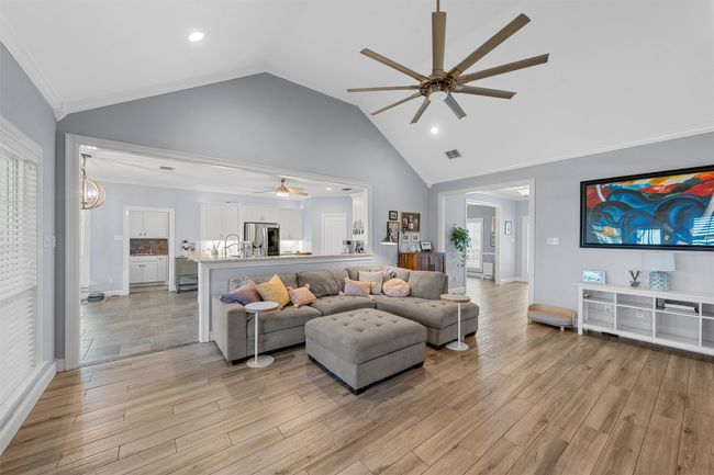 Living room featuring visible vents, ceiling fan, light wood-type flooring, crown molding, and high vaulted ceiling | Image 12