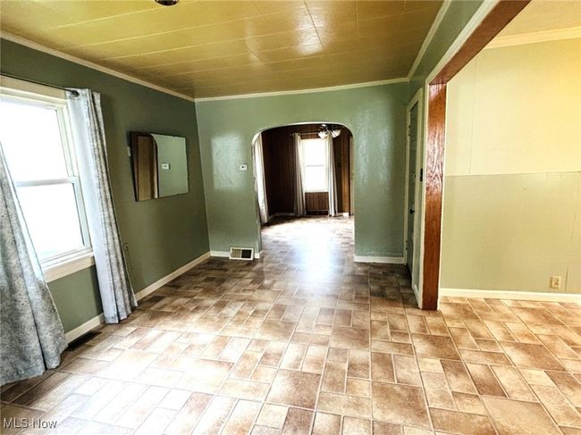 Hall with arched walkways, brick patterned flooring, ornamental molding, and baseboards | Image 6