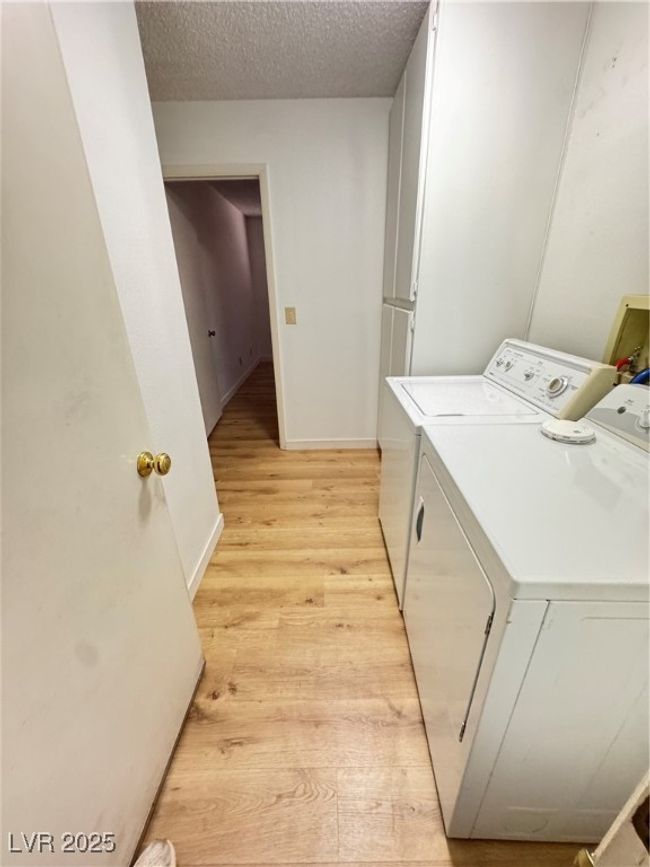 Washroom with washer and dryer, light wood finished floors, and a textured ceiling | Image 30
