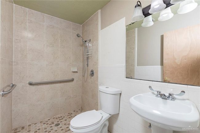 Bathroom featuring tiled shower, wainscoting, and tile walls | Image 17