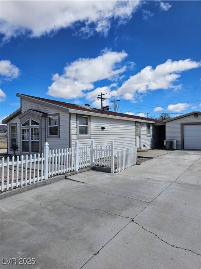 View of front of house with central air condition unit, driveway, and a fenced front yard | Image 7