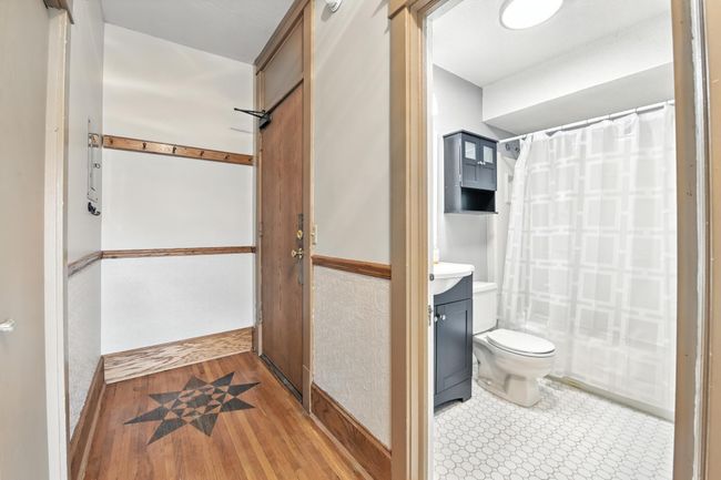 Welcoming entry foyer with coat hooks, decorative wood trim, and original inlay floor detail, conveniently located next to the bathroom. | Image 24