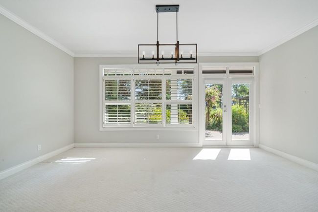 Unfurnished dining area featuring crown molding, a notable chandelier, and carpet | Image 9