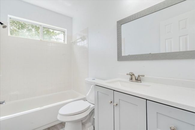 The guest bathroom features a new vanity cabinet with sink, complemented by new faucets, a mirror, towel bar, and towel ring. It also includes a new toilet and a bathtub with a tiled wall. | Image 18