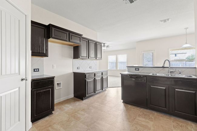 Kitchen with dishwasher, a sink, backsplash, ceiling fan, and baseboards | Image 22
