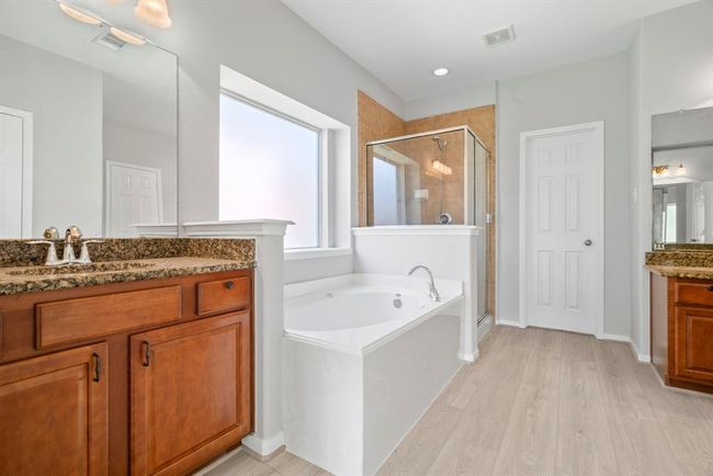 The luxurious master bathroom offers a spa-like retreat with elegant finishes throughout. Enjoy the comfort of dual vanities, a spacious walk-in shower, and a deep soaking tub perfect for unwinding. Large walk-in closet complete this serene and stylish space designed for relaxation and convenience. | Image 19