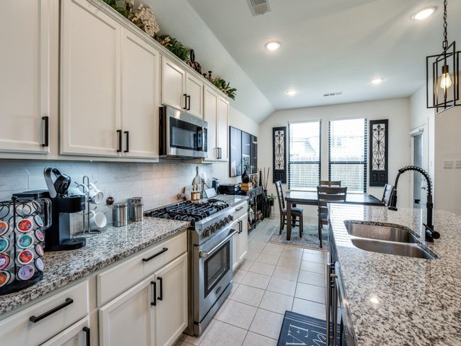 Kitchen featuring a sink, tasteful backsplash, visible vents, decorative light fixtures, and appliances with stainless steel finishes | Image 18