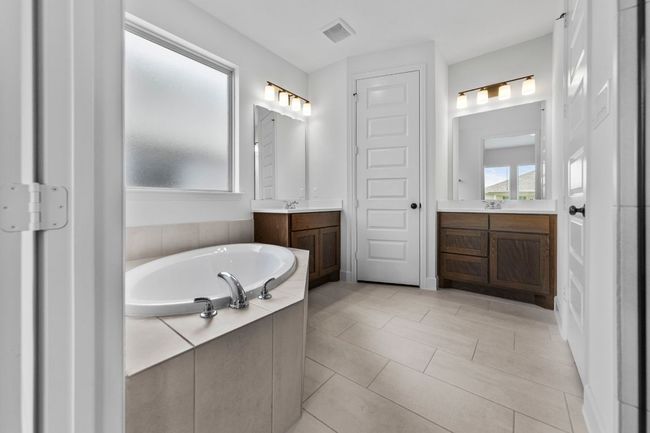 Full bathroom featuring a bath, two vanities, and tile patterned flooring | Image 15