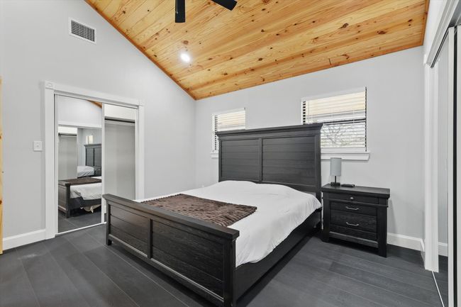Bedroom with visible vents, dark wood finished floors, lofted ceiling, wooden ceiling, and a closet | Image 22
