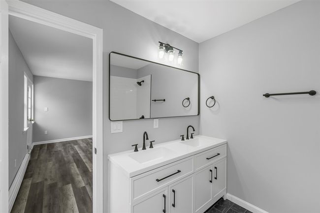 Bathroom with baseboards, wood finished floors, double vanity, and a sink | Image 24