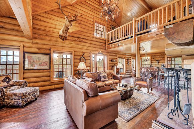 Living room featuring a chandelier, a wood ceiling with exposed beams, high vaulted ceiling, hardwood / wood-style floors, and log walls | Image 5