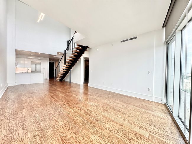 Unfurnished living room with stairway, light wood-type flooring, plenty of natural light, and baseboards | Image 4