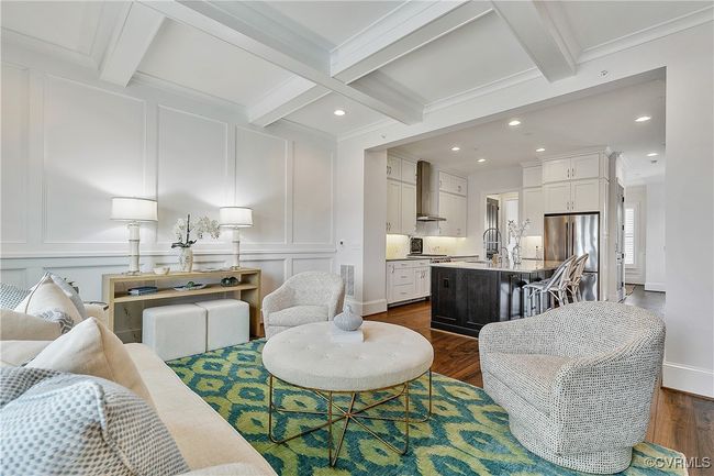 Living room with a decorative wall, dark wood-type flooring, visible vents, beamed ceiling, and crown molding | Image 13