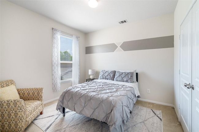 This cozy bedroom features soft carpet flooring, a ceiling fan for added comfort, and a window with privacy blinds to let in natural light while maintaining your personal space. | Image 7