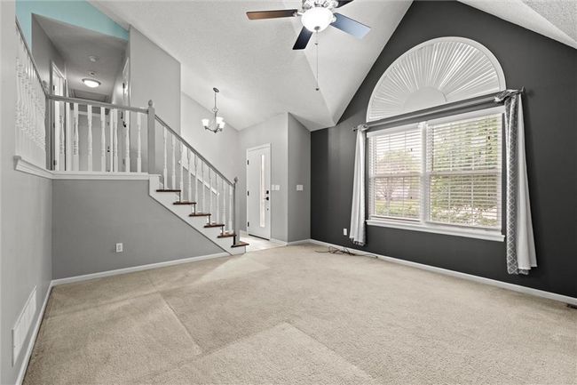 Entryway featuring carpet, a ceiling fan, vaulted ceiling, a chandelier, and stairway | Image 7