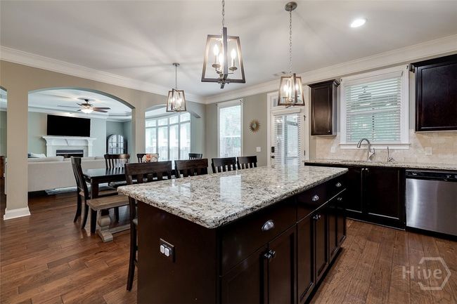 Open concept floor plan where the kitchen flows to the breakfast bar, kitchen table and living room. Sink looks out to screen porch and backyard. | Image 17
