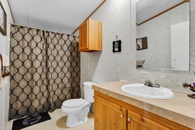 Bathroom featuring toilet, a shower with curtain, tile patterned flooring, and vanity | Image 19