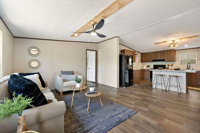 Living area with wood finished floors, a ceiling fan, and ornamental molding | Image 11