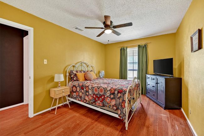 Bedroom with a textured ceiling, wood finished floors, a ceiling fan, and a textured wall | Image 17